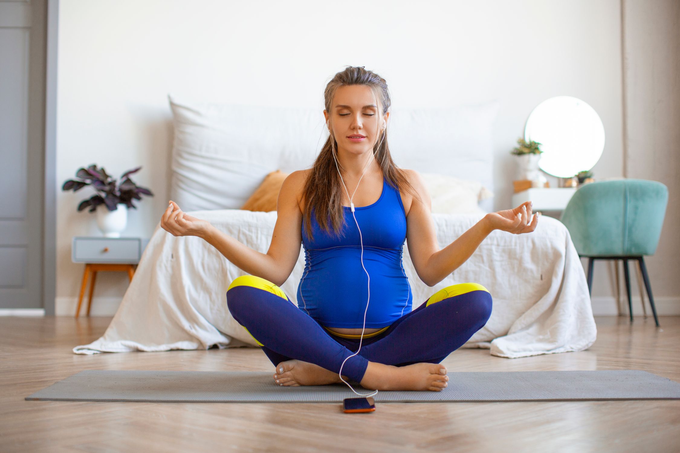 pregnant woman doing relaxation exercises lotus position listening music