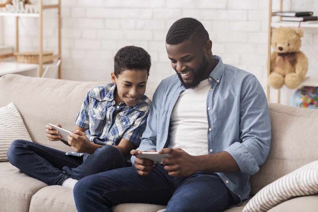 cheerful black boy and his dad playing video games 24C5BZK